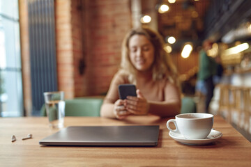 Woman sitting at cafe and using smartphone