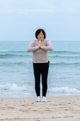 Mature asian woman practicing meditation near the sea. Selective focus.