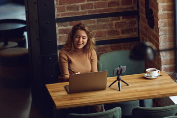 Smiling woman sitting at table with laptop and smartphone