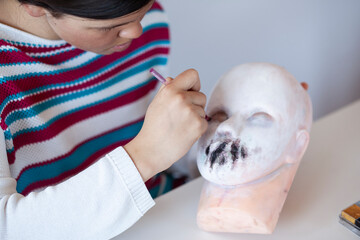 Girl doing SFX makeup on a training rubber head for makeup