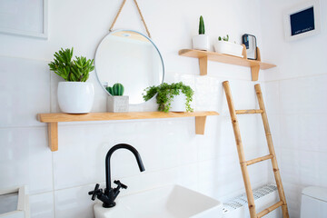 Small rustic bathroom in a cottage with white tiles on a wall with wooden ladder and shelf with...