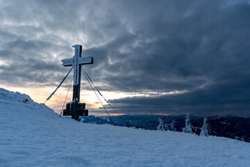 summit cross at "Rennfeld" mountain near the city Bruck an der Mur in Styria, Austria at sunset in winter