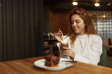 Relaxed woman enjoying coffee and dessert at cafe