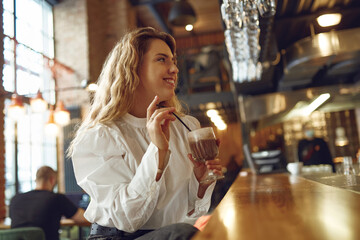 Side view of woman sitting at cafe and drinking coffee