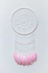 Handmade dream catcher with feathers threads and beads rope hanging on white background