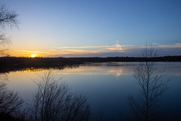 Dramatic and colorful sunset over a forest lake reflected in the water. Blakheide, Beerse, Belgium. High quality photo