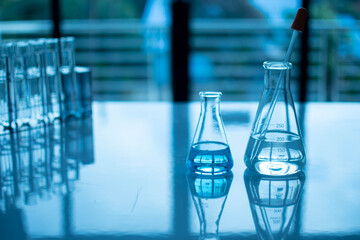 Chemistry experiment concept in science laboratory monkeypox virus. Two science flasks of different sizes contain different chemicals. The chemicals are in many glass tubes on table and blurred.