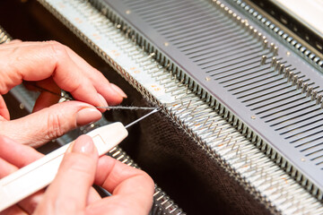Womans hands working with knitting machine