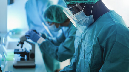 Medical doctors workers in hazmat suit working with computer and micoroscope inside hospital lab...