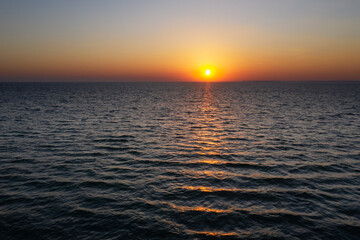 Sunset in the ocean with large sun dusk soft waves and red cloudy sky. Sea sunrise background. Landscape photography