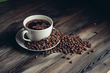 saucer with coffee beans and white cup on a wooden table side view Copy Space