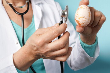 doctor with stethoscope holding Easter pink egg on blue background