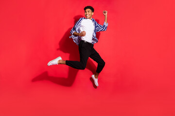 Fototapeta na wymiar Full size photo of young excited black man happy positive smile jump up celebrate victory isolated over red color background