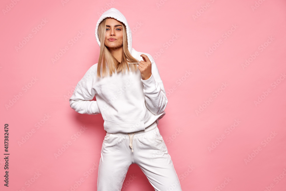 Wall mural Beautiful blonde woman wear of white set of track suit isolated on pastel background