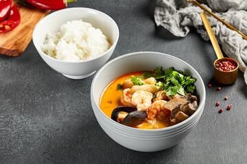 Tom yum soup with spicy seafood. Grey bowl on dark slate table. Thai, asian, authentic food concept