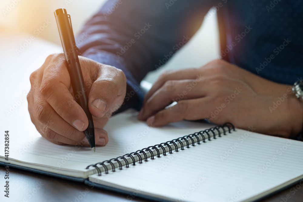 Wall mural close-up of man hand using writing pen memo on notebook paper or letter, diary on table desk office.