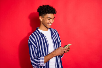 Profile side photo of black guy happy smile browse cellphone chat type sms isolated over red color background