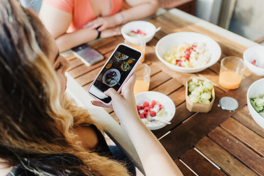 Young woman taking picture of healthy breakfast
