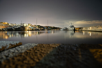 Fototapeta na wymiar Long exposure at night at the Port of Portals in Calvia with a lighthouse, Palmanova and the stars in the background in Palma de Mallorca, Spain