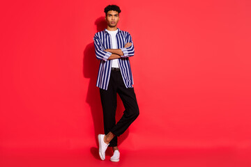 Full length photo of young handsome black man confident serious folded hands isolated over red color background