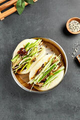 Bao bun with roast duck. Bamboo steamer on dark slate table. Chinese, asian, authentic food concept
