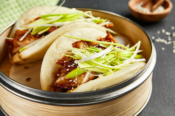 Bao bun with hoisin chicken. Bamboo steamer on dark slate table. Chinese, asian, authentic food...