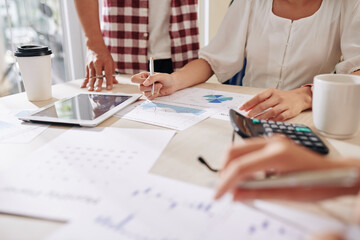 Close-up image of business people discussing reports and diagrams at meeting