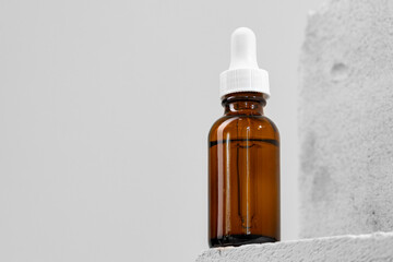 Glass jar of skincare serum on concrete block