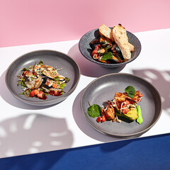 Restaurant food - Seafood plate assortment with shrimp and vegetable. Shellfish appetizer food plate on white table with pink wall. Day sunlight with hard shadow of tropic leaves. Summer food concept.
