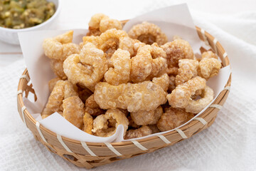 Perfect pork scratchings or pork cracklings served in a bamboo basket together with hot green chili dip. It is a popular Thai food dish from northern Thailand.