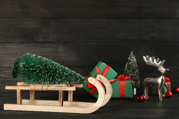 Beautiful Christmas composition with miniature sleigh on black wooden table. Space for text