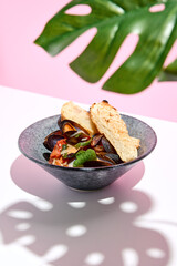 Mussel with bread restaurant plate. Restaurant appetizer plate on white table with pink wall. Day sunlight with hard shadow of monstera palm leaves. Summer or spring restaurant food concept.