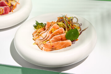 Salmon tataki in sesame with salad. Fish sashimi restaurant appetizer on white table with green...