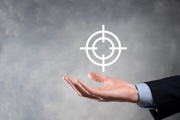 Targeting concept with businessman hand holding target icon dartboard sketch on chalkboard. Objective target and investment goal concept.