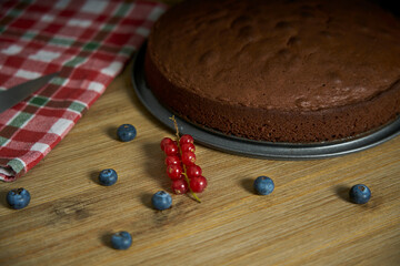 A proud cook woman shows the homemade chocolate cake she has just baked in her kitchen. She will...