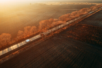 Aerial view of minivan on the road in sunset, drone pov