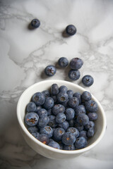 A group of fresh blueberries on a white and black marble table. 
