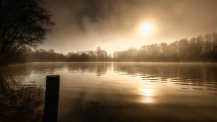 Sunrise over Westport lake in Stoke on Trent, Staffordshire, UK, on a foggy morning.Tranquil landscape scenery during golden hour.Beautiful and ethereal nature scene.