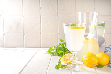 Iced homemade lemonade drink, limoncello liqueur cocktail decorated with mint and lemons on white...