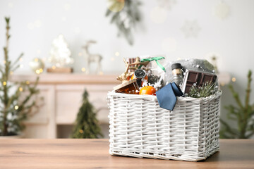 Wicker basket with Christmas gift set on wooden table. Space for text