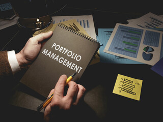 Man makes notes about portfolio management in the notepad. - obrazy, fototapety, plakaty