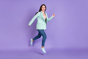 Full size profile side photo of brunette lady jump up go empty space wear teal coat jeans isolated on violet color background