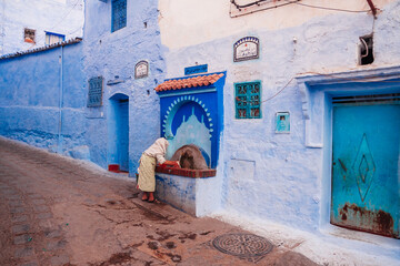 grandmother washes her hands under the tap on the street of the city
