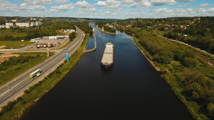 Aerial view:Barge with cargo on the river. River, cargo barge, highway with cars.. Cargo ship on the river.
