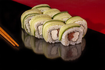 Sushi Sets Uramaki, California, Philadelphia, on a white plate. Festive new year concept. Against a dark reflective background.