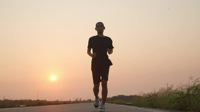 Silhouette Asian runner runs on street in countryside with fresh and clear air, man running or workout for good healthy in sun set, healthy care concept
