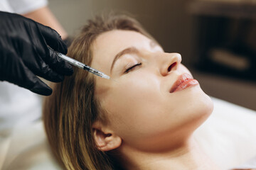 Anti-aging injections beauty treatment. Close-up of a young woman s face lying on back, getting face lifting injection