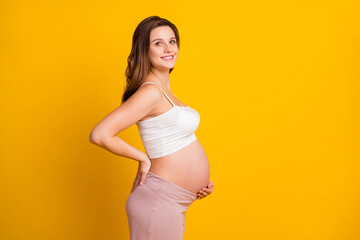 Photo of charming sweet woman expecting child wear white outfit hugging belly isolated yellow color background