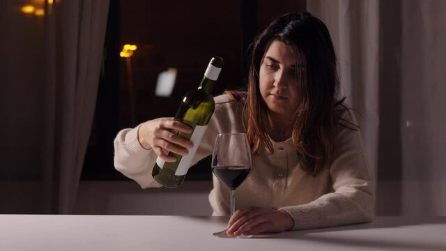 alcoholism, alcohol addiction and people concept - drunk woman or female alcoholic drinking red wine at home at night