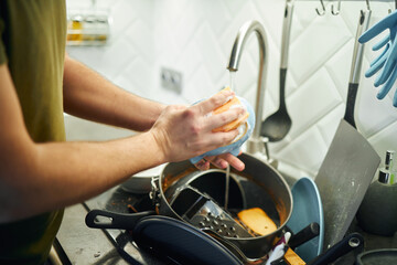 Young man washing dishes in the kitchen.